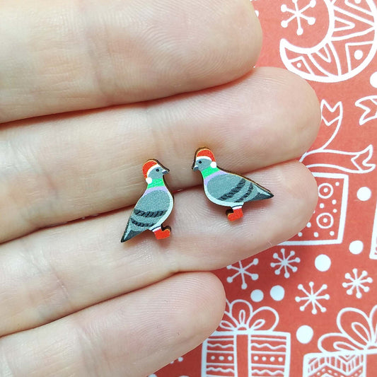 Christmas pigeon wooden stud earrings held on hand, the pigeons are wearing red santa hats and red boots