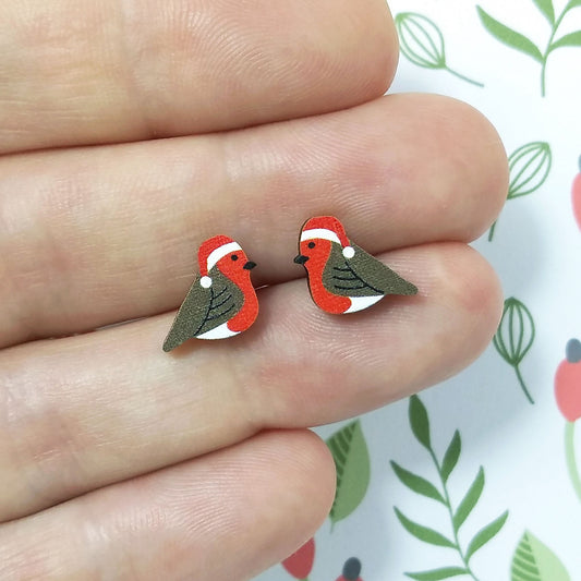 Christmas robin wooden stud earrings held on hand, the robins are wearing red santa hats