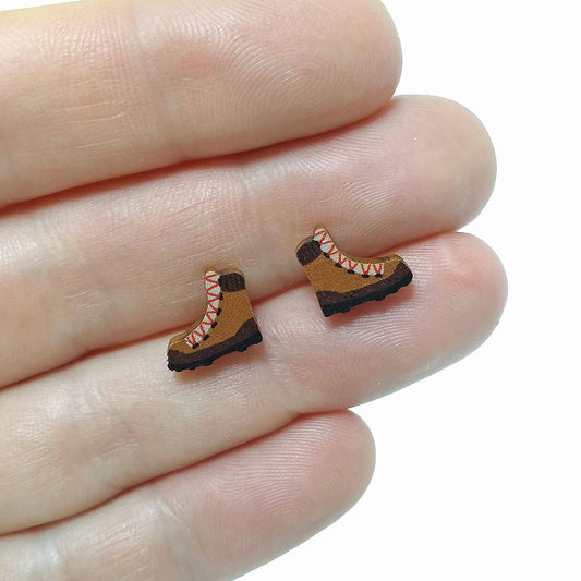 Wooden hiking boot stud earrings held on hand