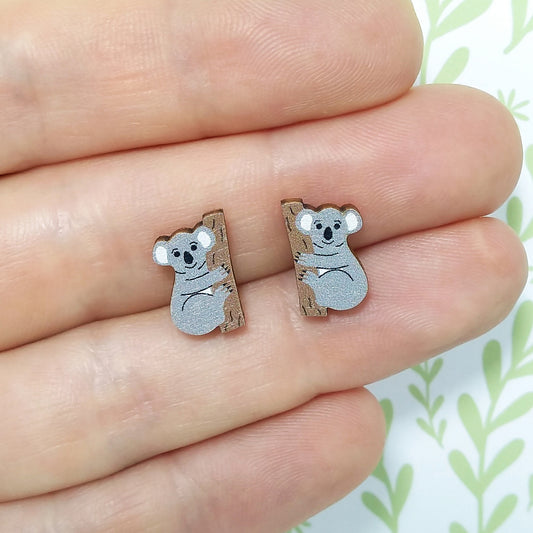 Wooden koala stud earrings held on hand