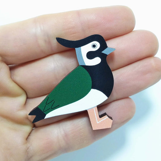 Wooden lapwing pin badge held on hand