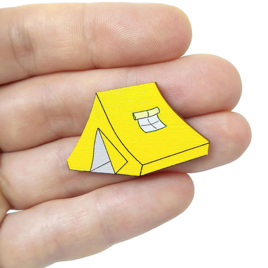 Wooden yellow tent pin badge held on hand
