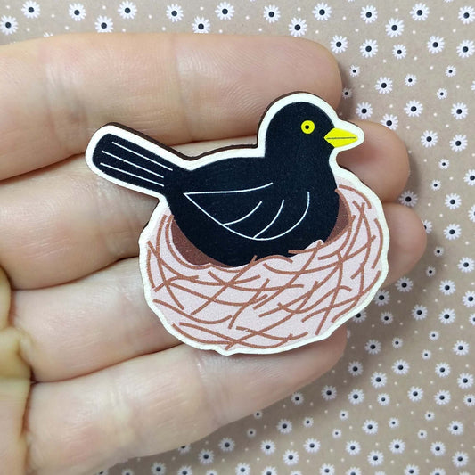 Wooden blackbird pin badge held on hand