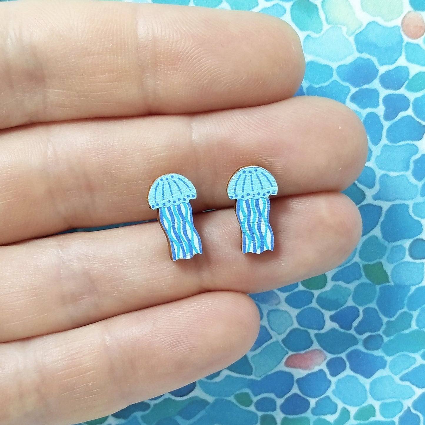 Wooden blue jellyfish stud earrings held on hand
