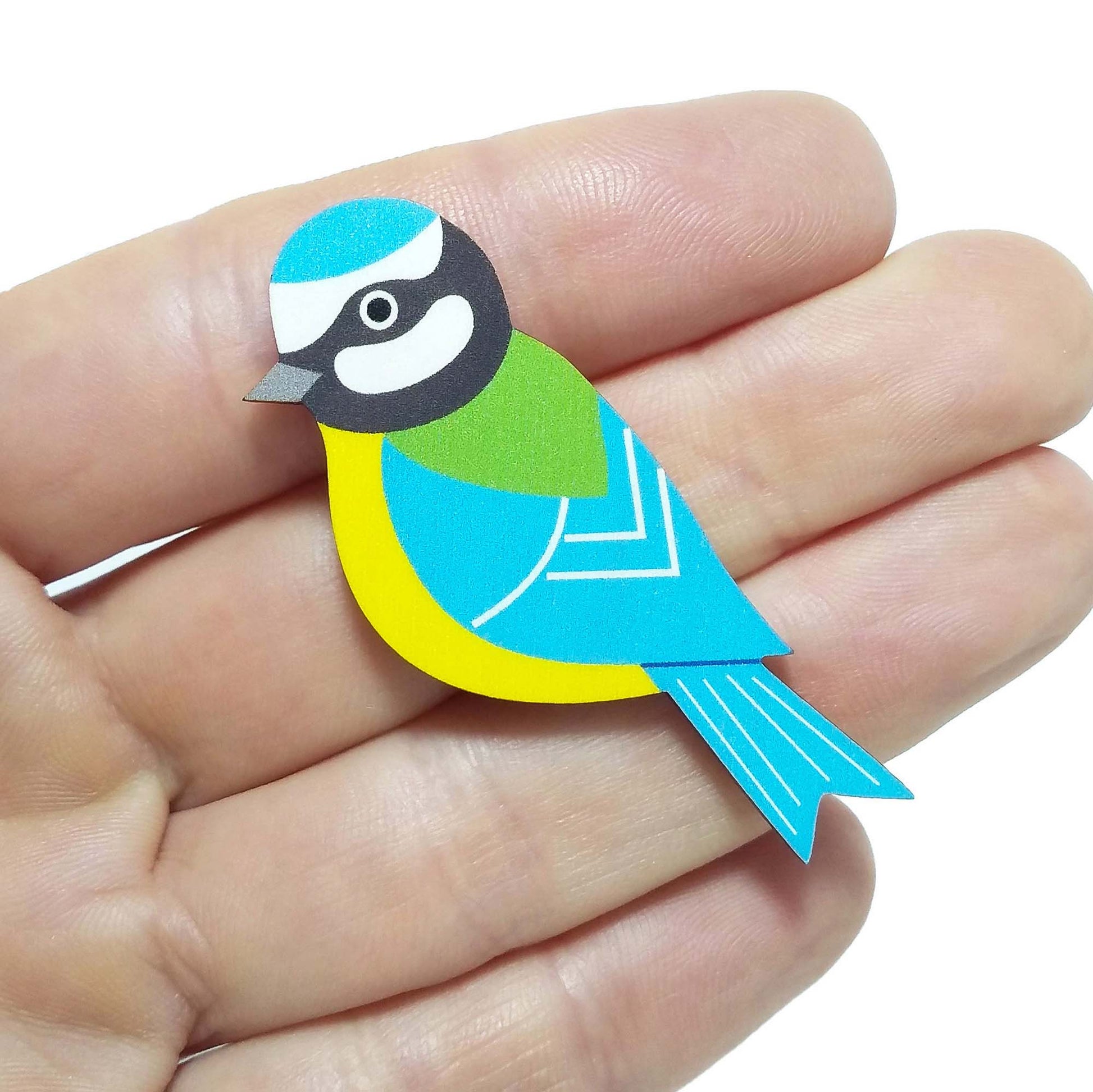 Wooden blue tit pin badge held on hand