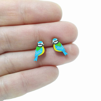 Wooden blue tit stud earrings held on hand, in yellow, blue, green and black