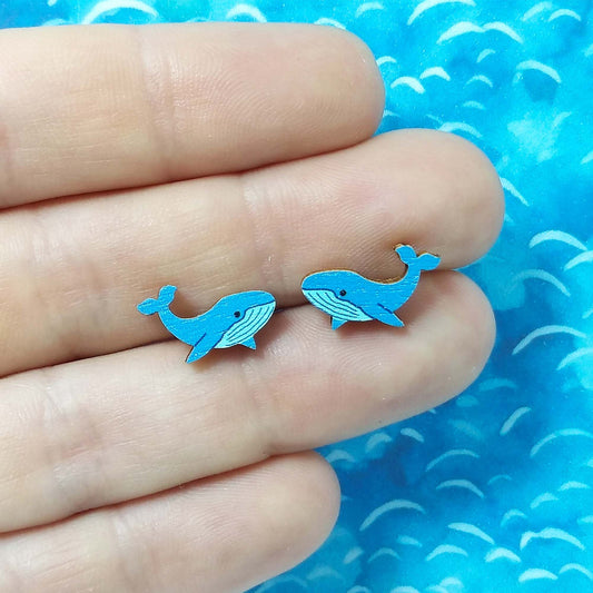 Wooden blue whale stud earrings held on hand