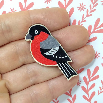 Wooden bullfinch pin badge held on hand