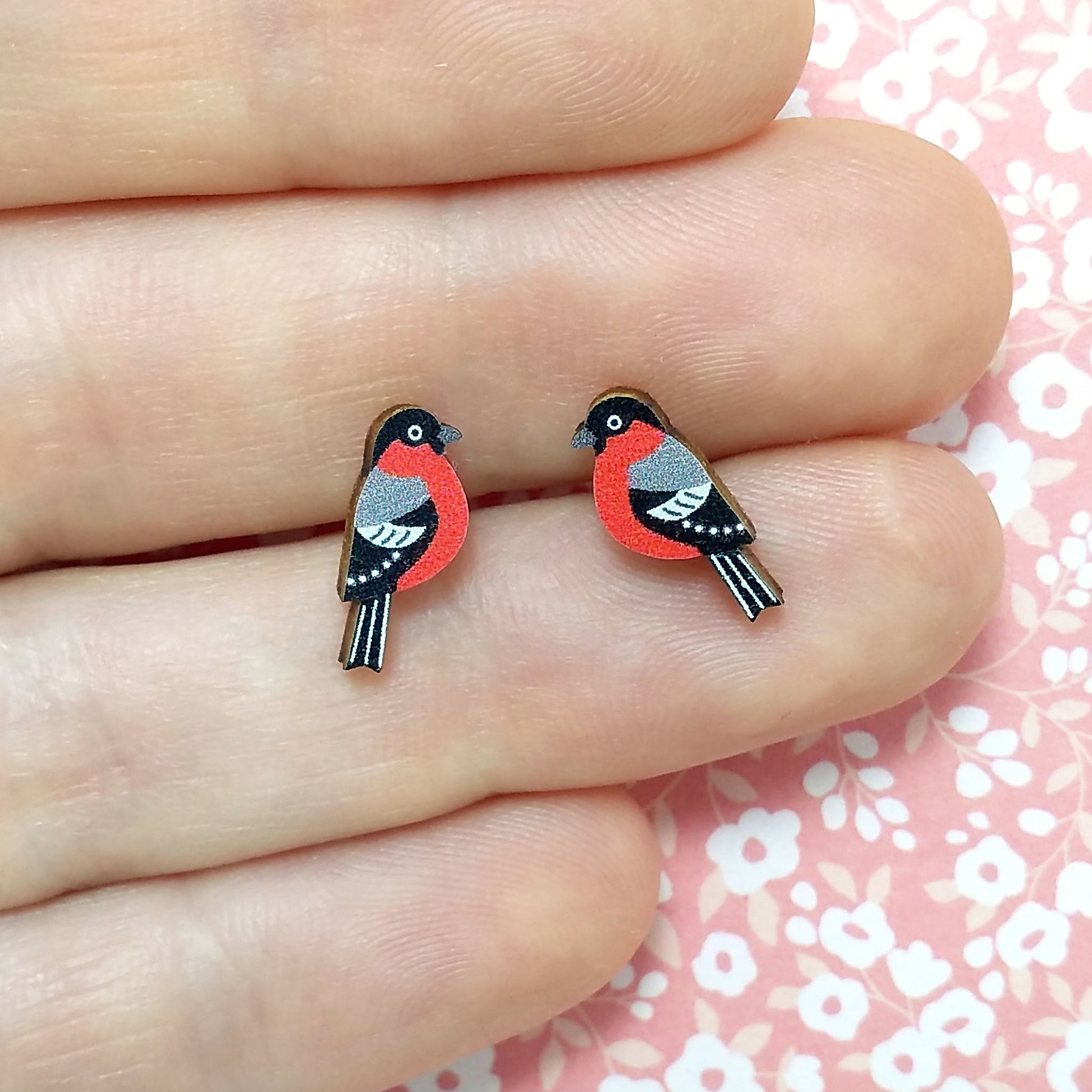 Wooden bullfinch stud earrings held on hand