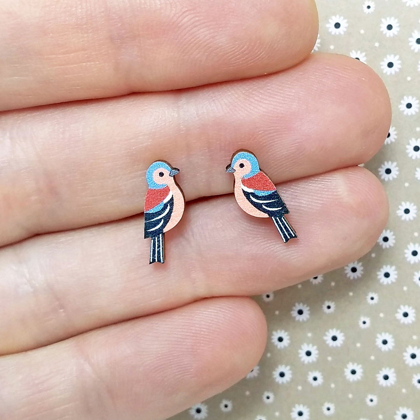 Wooden chaffinch stud earrings held on hand
