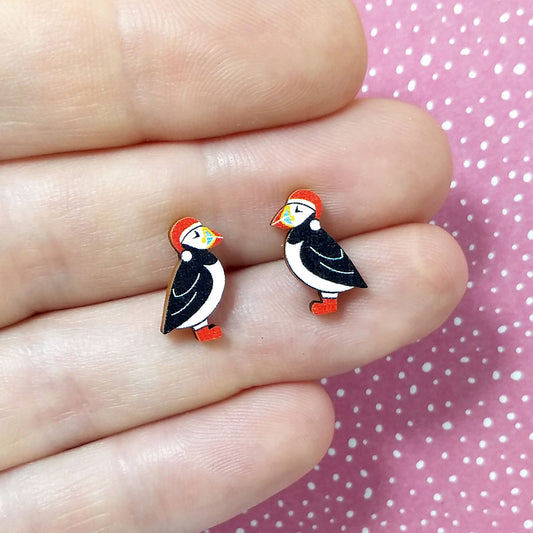 Christmas puffin wooden stud earrings held on hand, puffins are wearing red santa hats and red boots