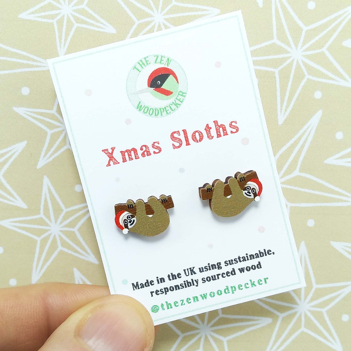 Christmas sloth stud earrings on display card, made of wood, the sloths are wearing red santa hats