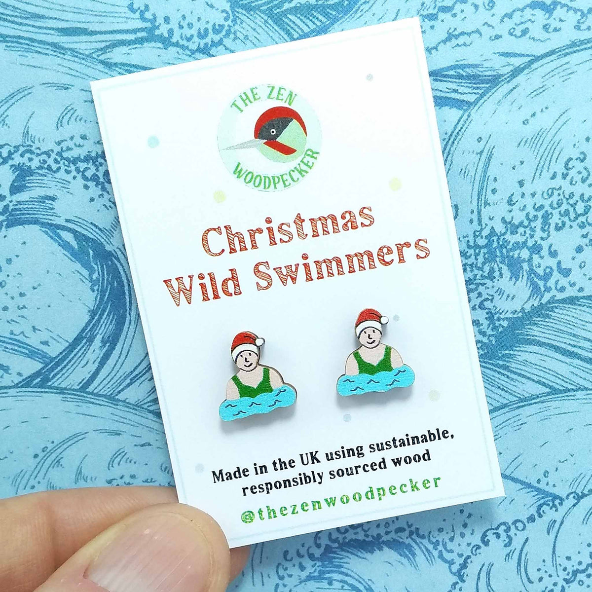 Christmas wild swimmer stud earrings on display card, made of wood, the swimmers are wearing red santa hats