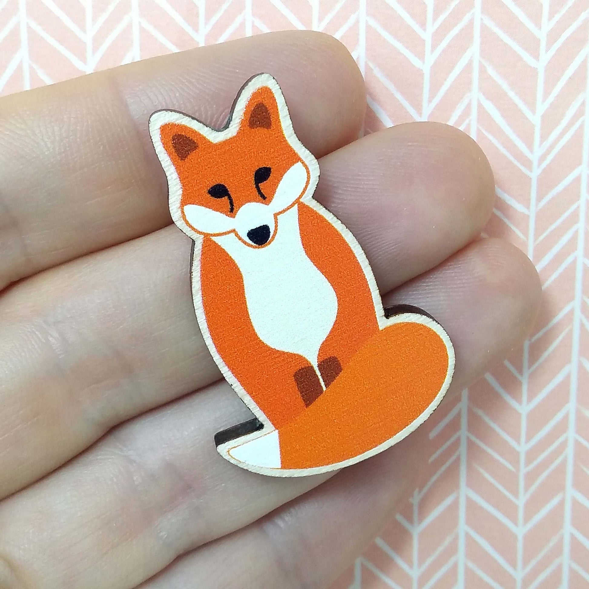 Wooden fox pin badge held on hand