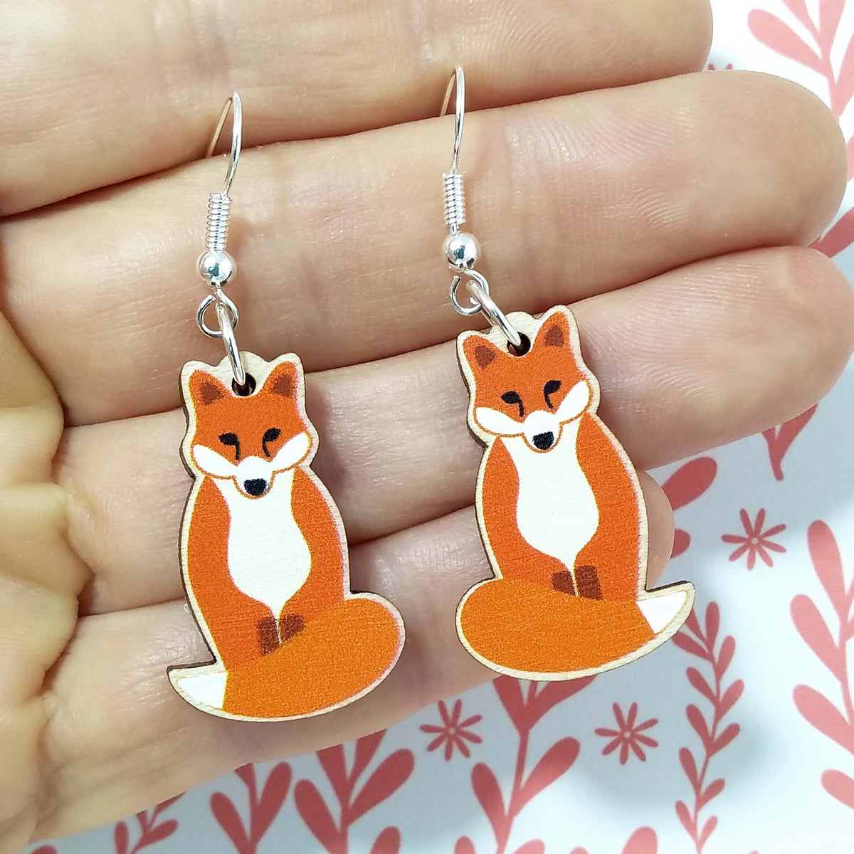 Wooden dangling fox earrings held on hand