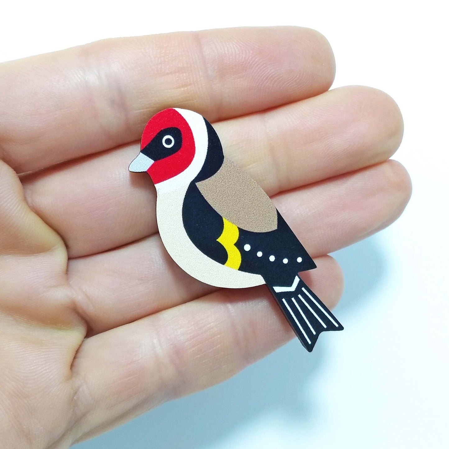 Wooden goldfinch pin badge held on hand