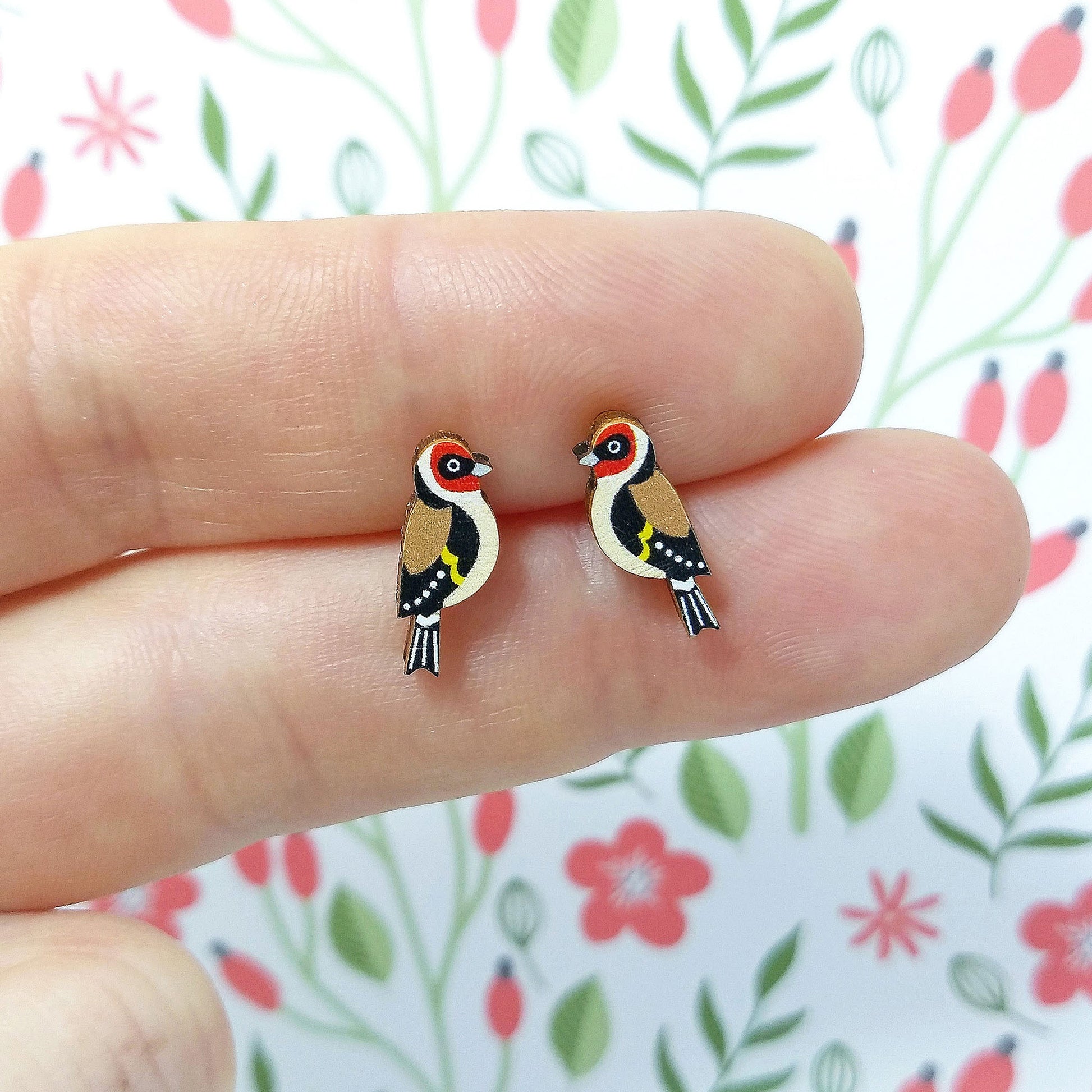 Wooden goldfinch stud earrings held on hand