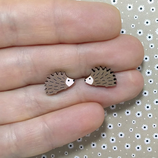 Wooden hedgehog stud earrings held on hand