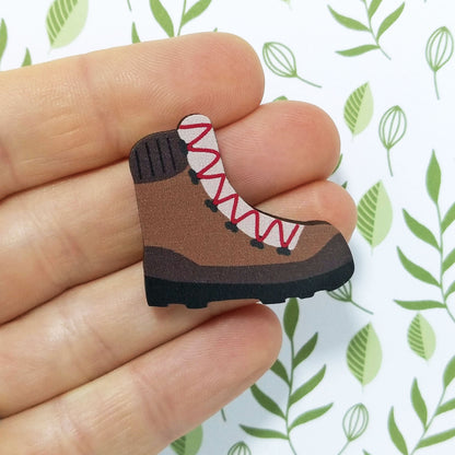Wooden hiking boot pin badge held on hand