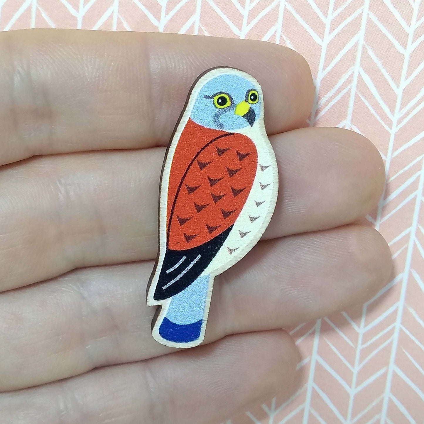 Wooden kestrel pin badge held on hand