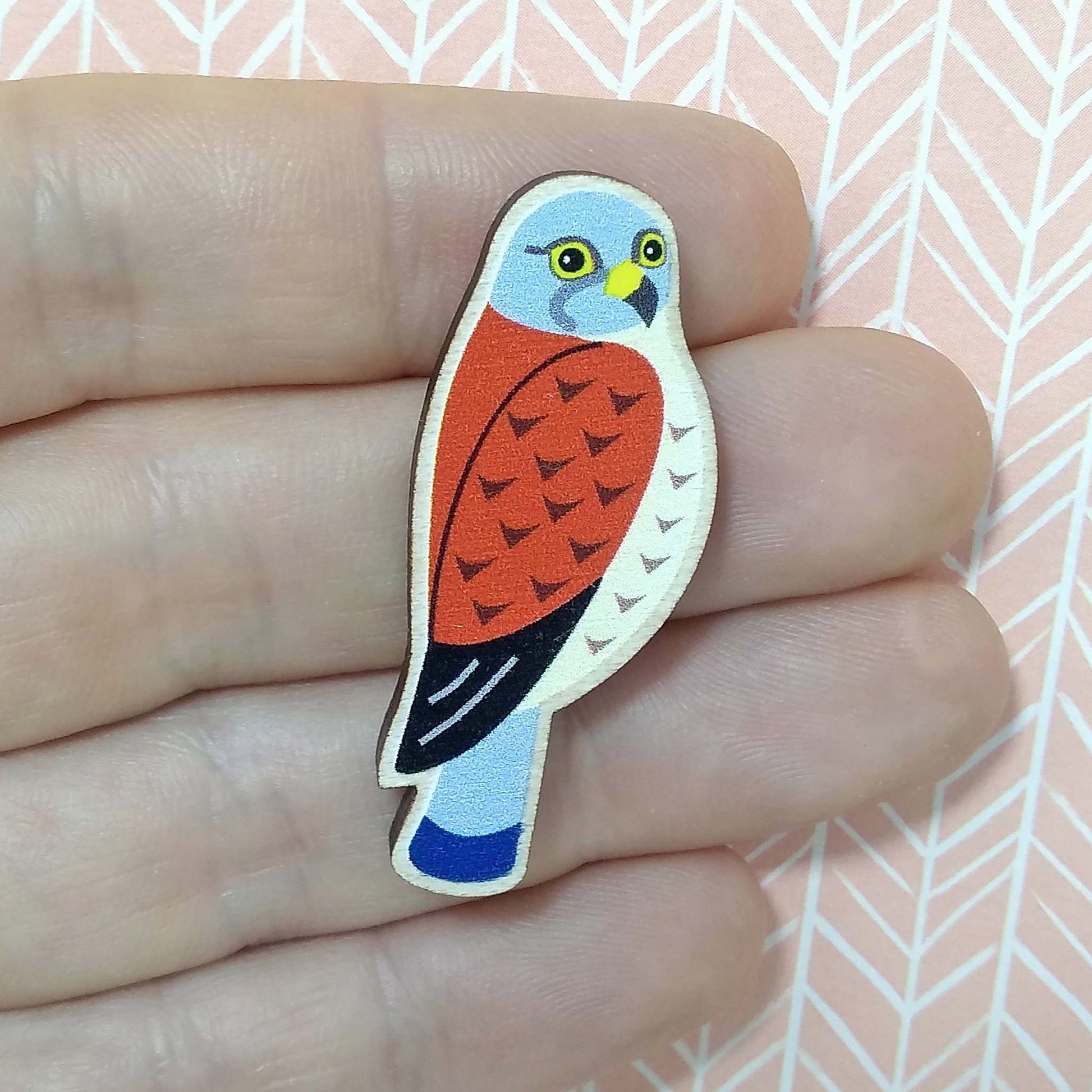 Wooden kestrel pin badge held on hand