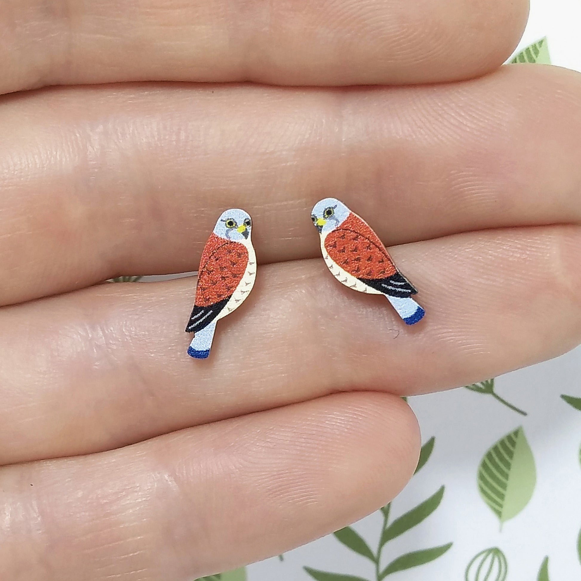 Wooden kestrel stud earrings held on hand