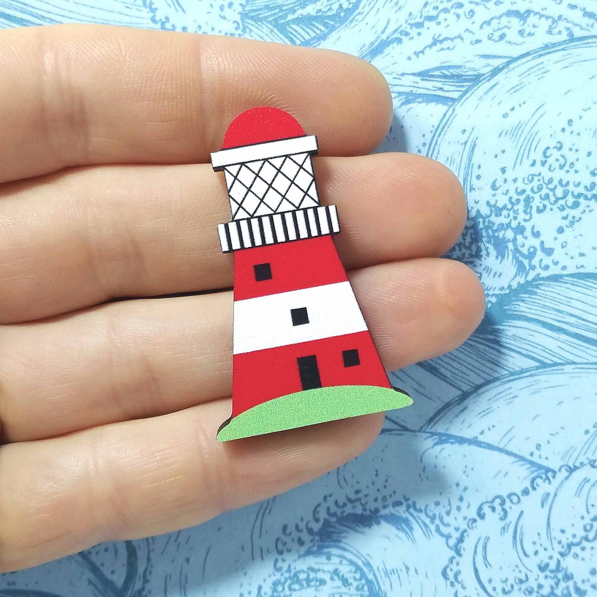Wooden lighthouse pin badge held on hand