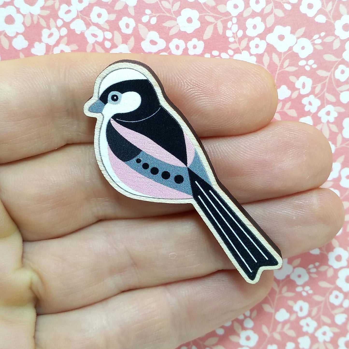 Wooden long tailed tit pin badge held on hand