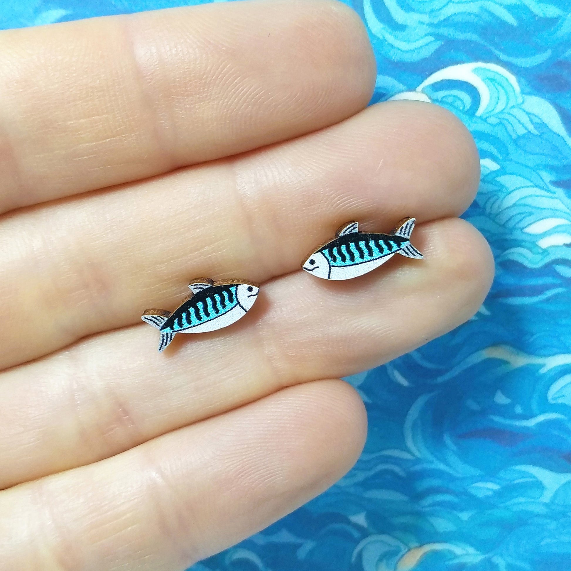 Wooden mackerel stud earrings held on hand