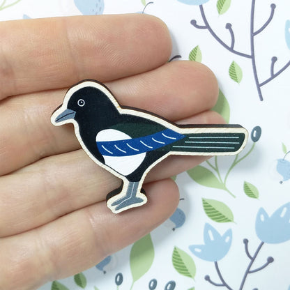 Wooden magpie pin badge held on hand