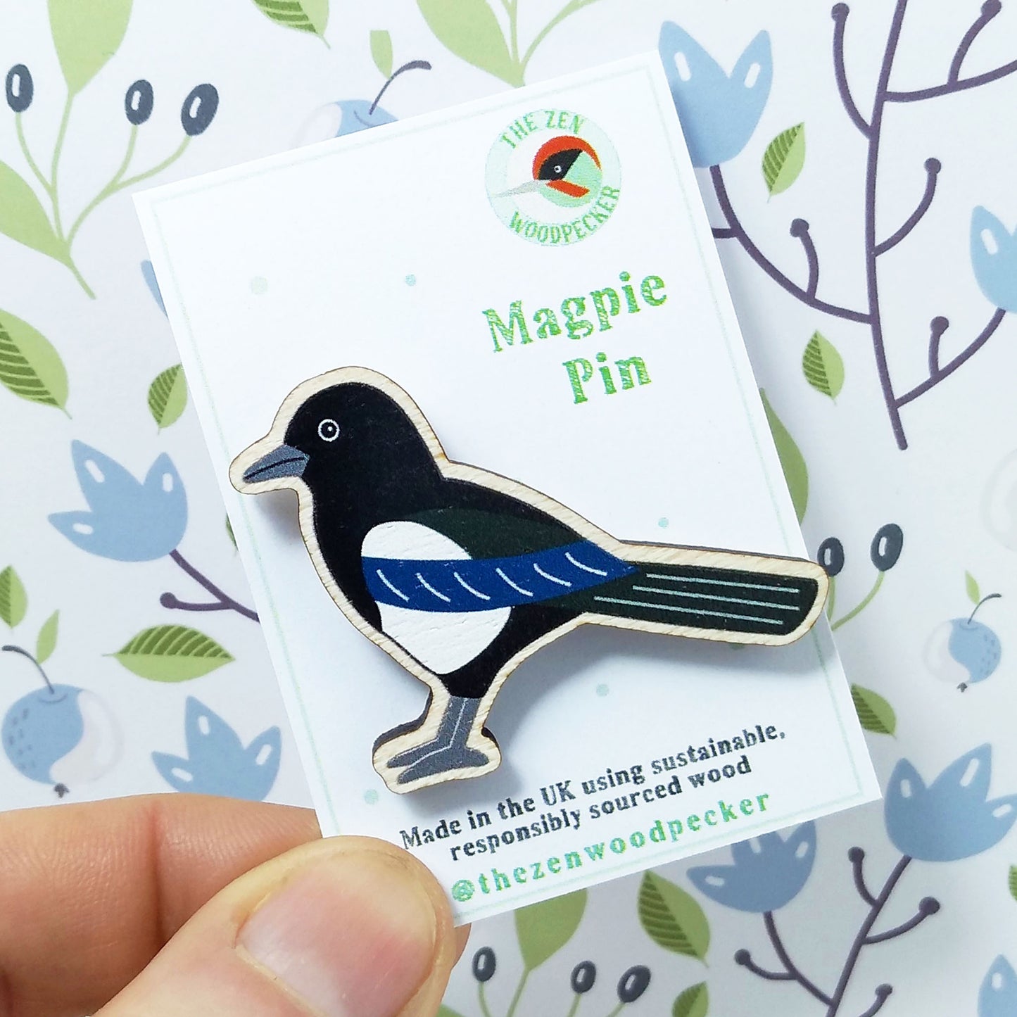 Wooden magpie pin badge on display card