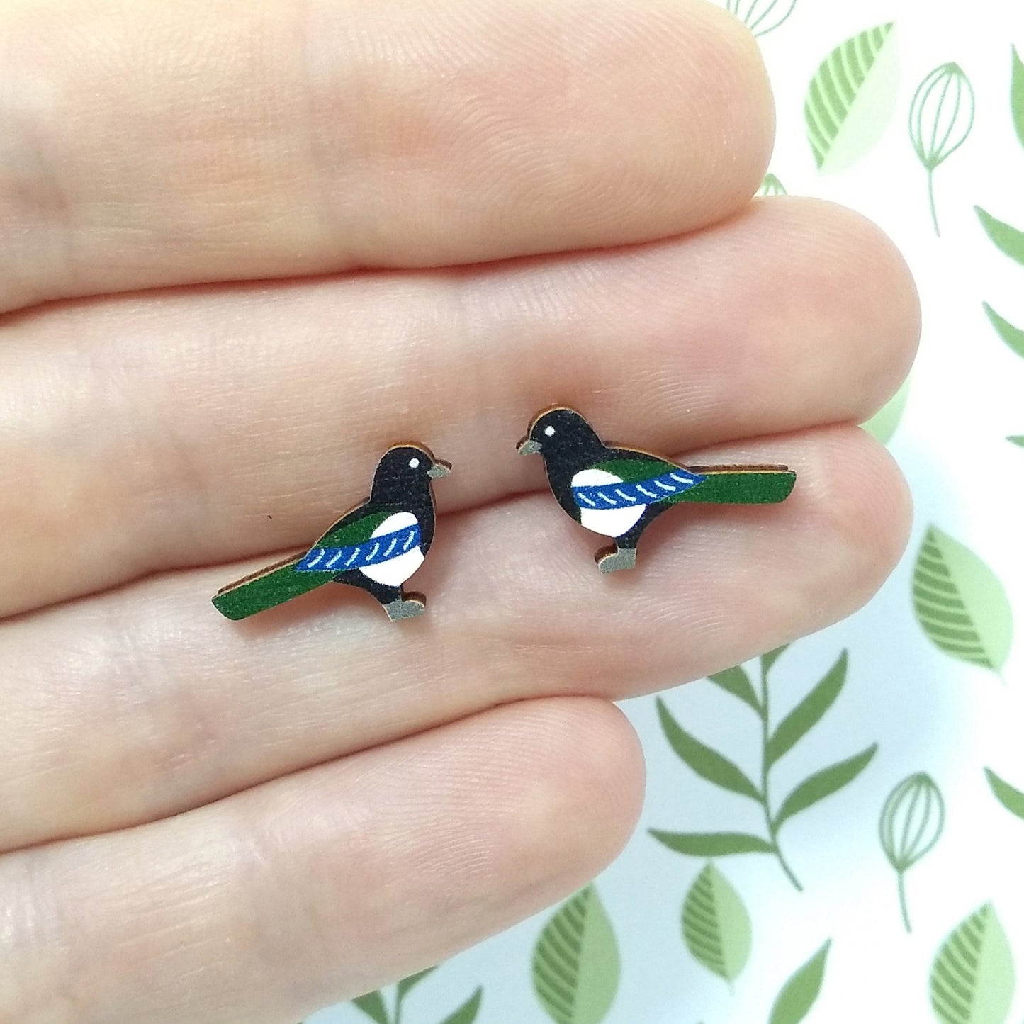 Wooden magpie stud earrings held on hand