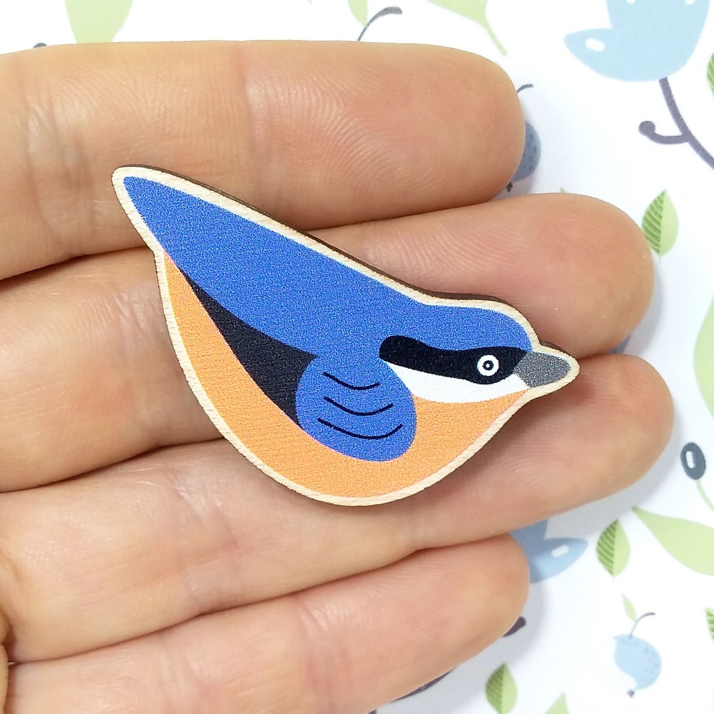 Wooden nuthatch pin badge held on hand