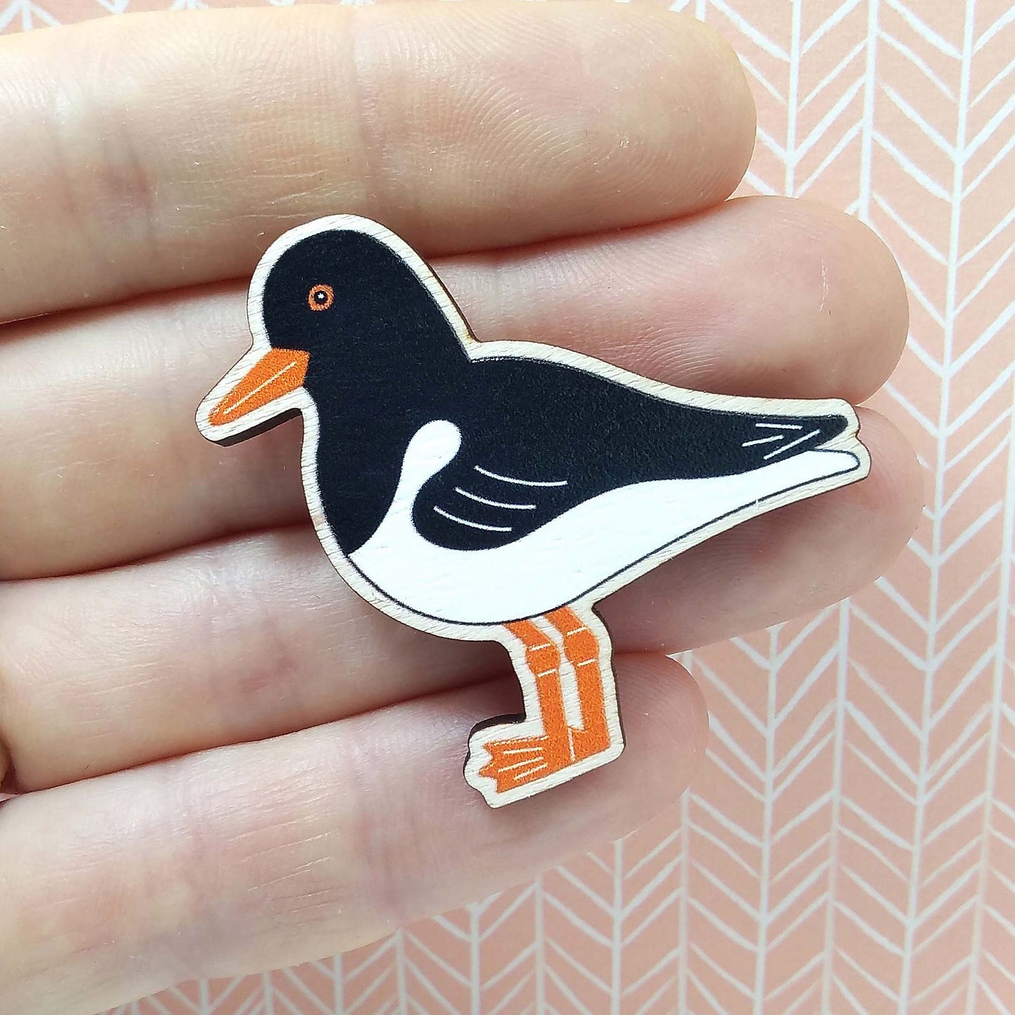 Wooden oystercatcher pin badge held on hand