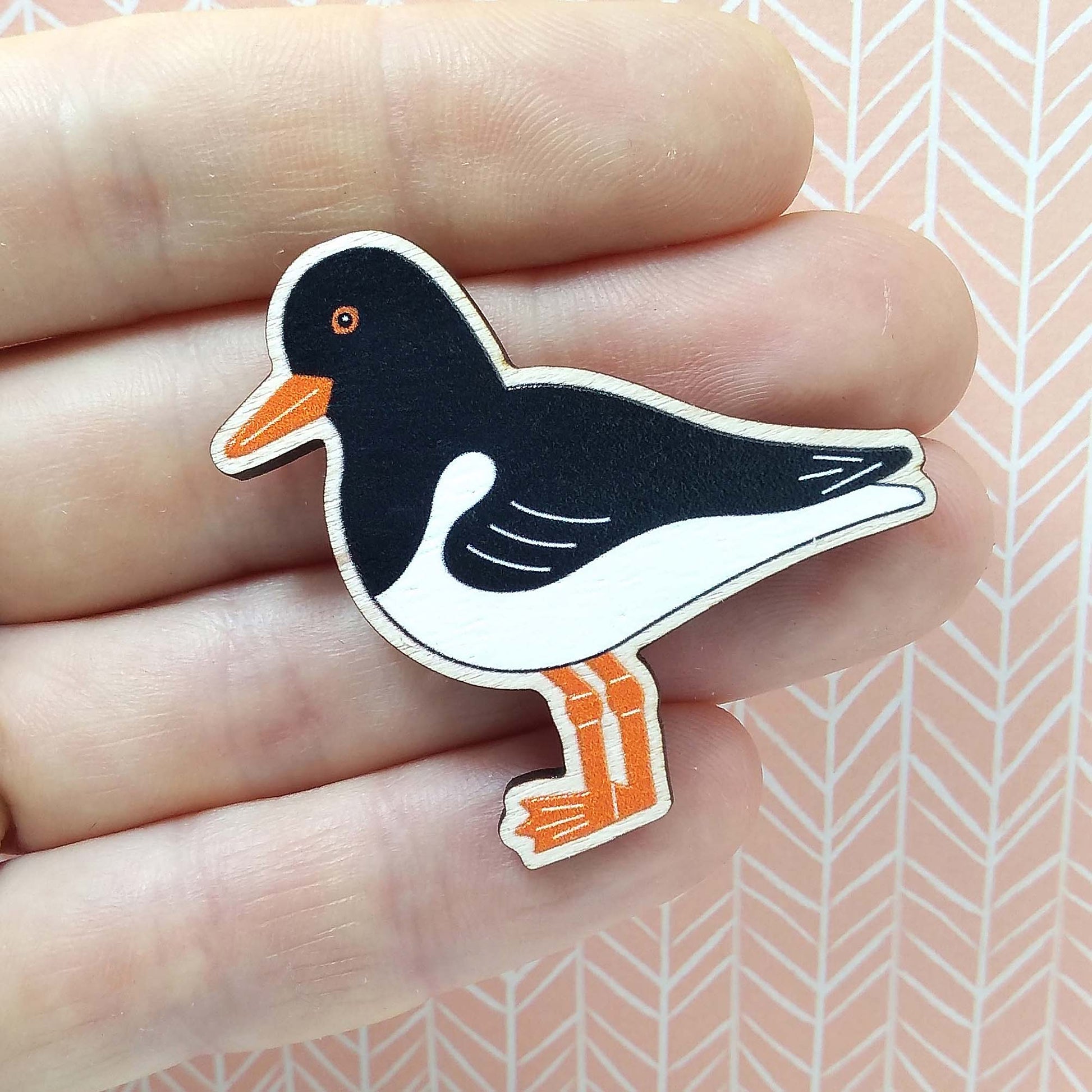 Wooden oystercatcher pin badge held on hand