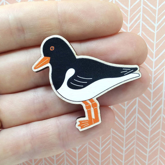 Wooden oystercatcher pin badge held on hand