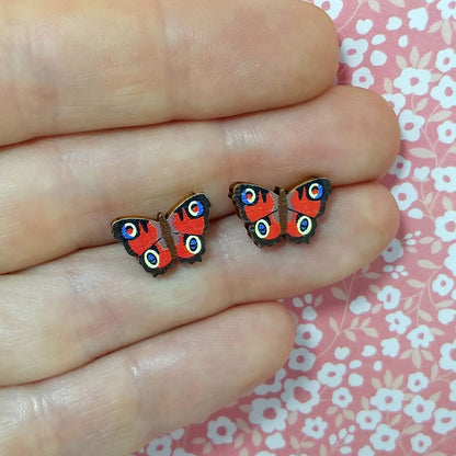 Wooden peacock butterfly stud earrings held on hand