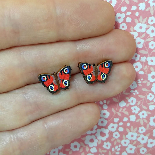 Wooden peacock butterfly stud earrings held on hand