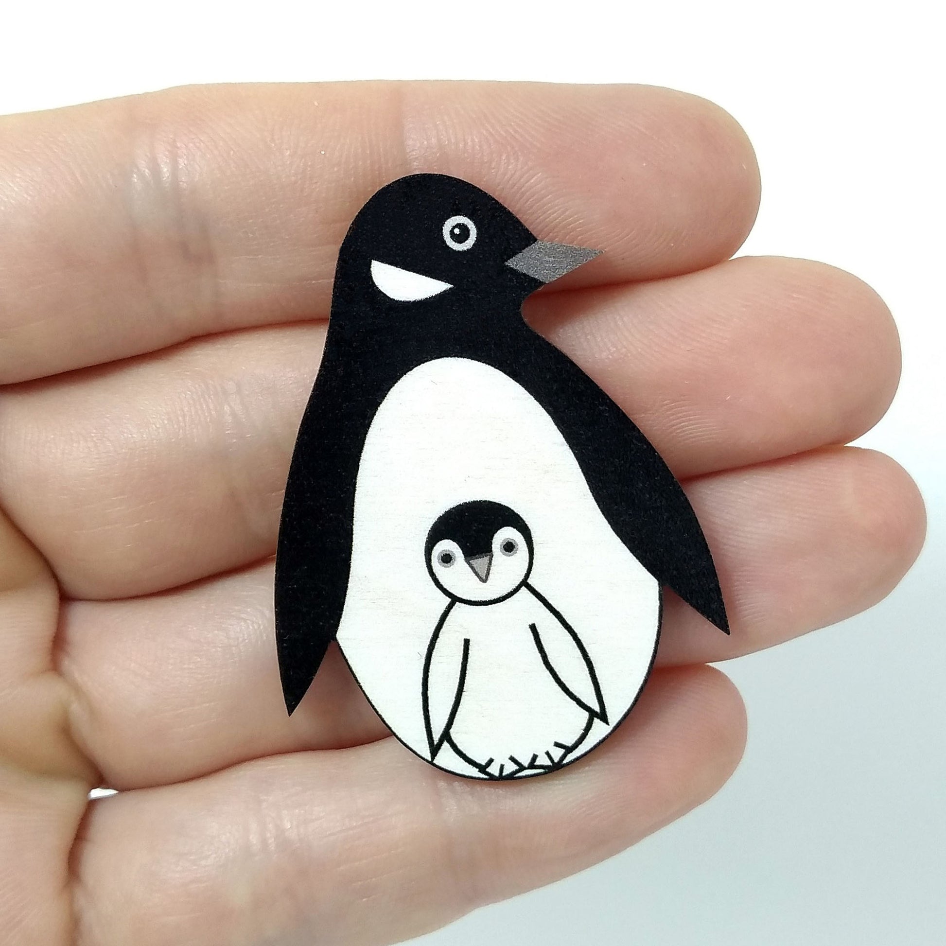 Wooden penguin pin badge held on hand