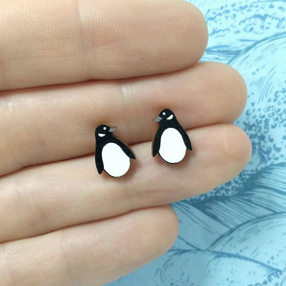 Wooden penguin stud earrings held on hand