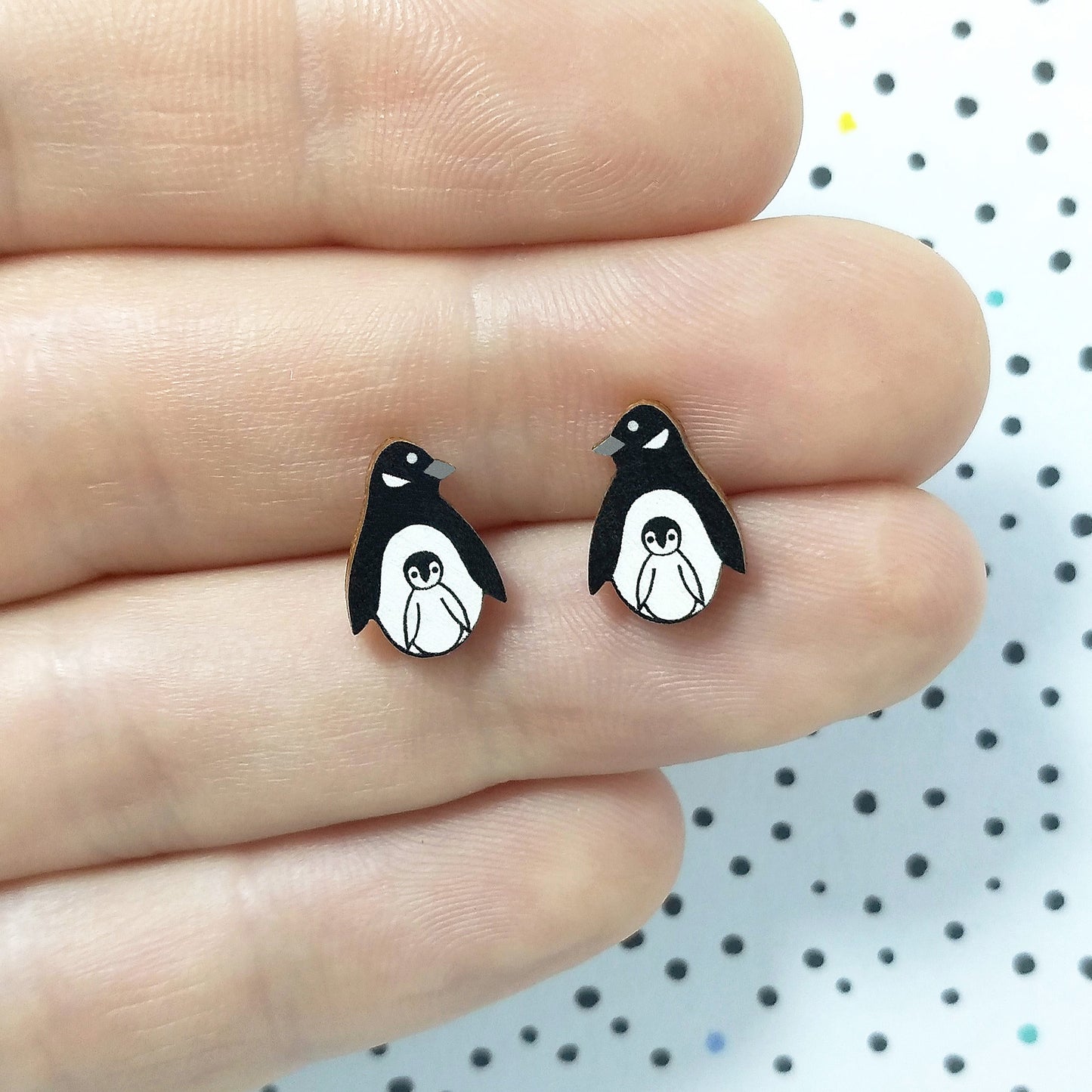 Wooden penguin with chick stud earrings held on hand