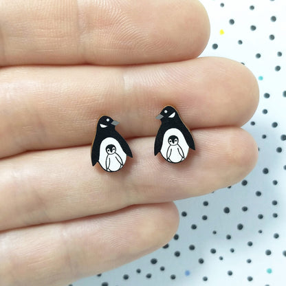 Wooden penguin with chick stud earrings held on hand