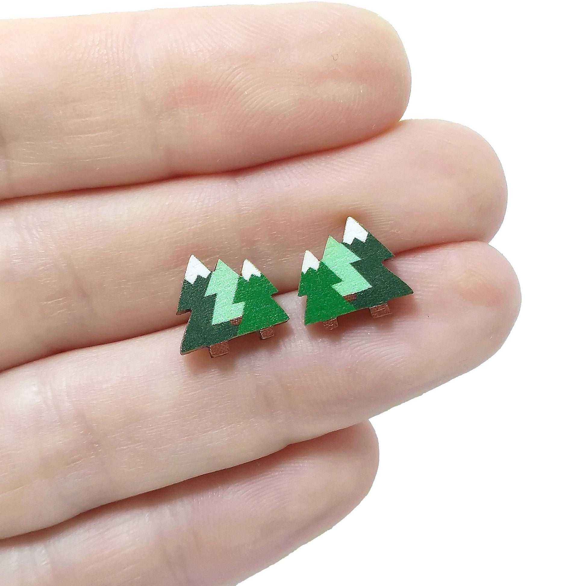 Wooden pine tree stud earrings held on hand
