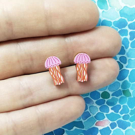 Wooden pink jellyfish stud earrings held on hand