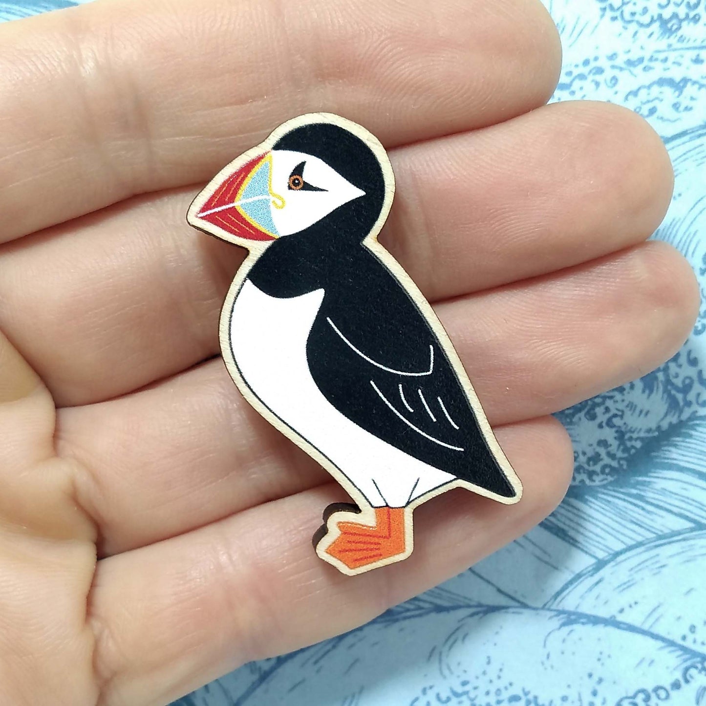 Wooden puffin pin badge held on hand