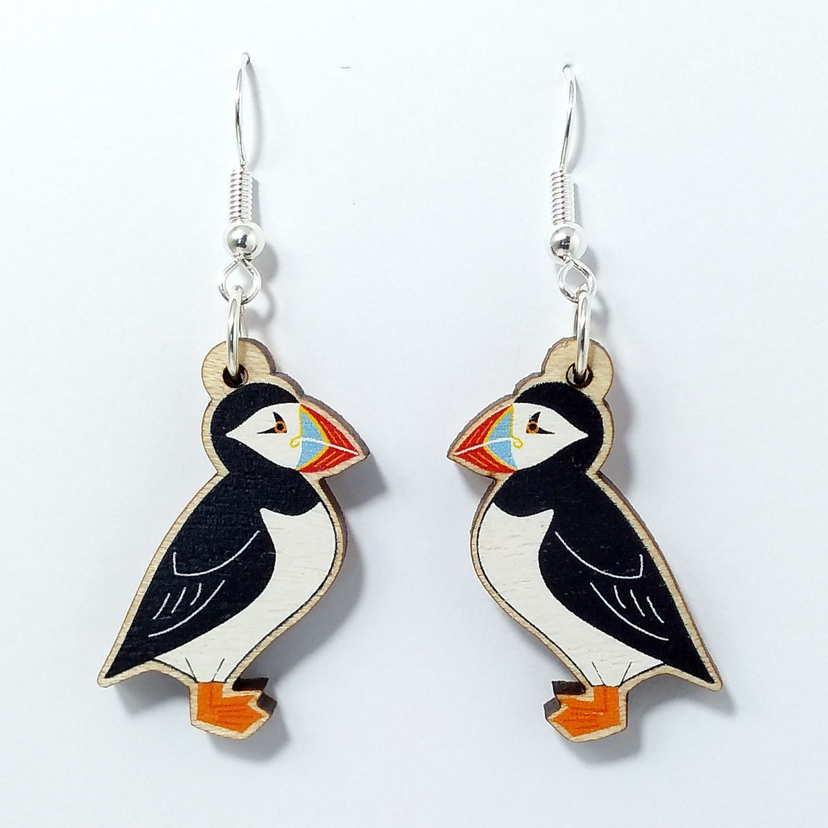 Wooden puffin dangle earrings on white background 