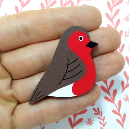 Wooden robin pin badge held on hand