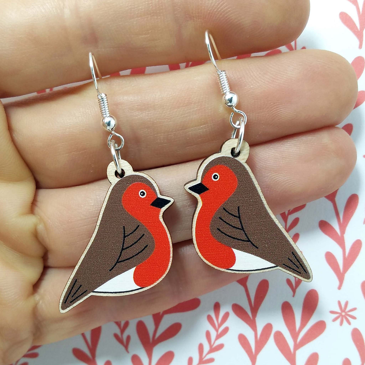 Wooden dangling robin earrings held on hand