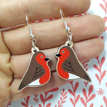 Wooden dangling robin earrings held on hand