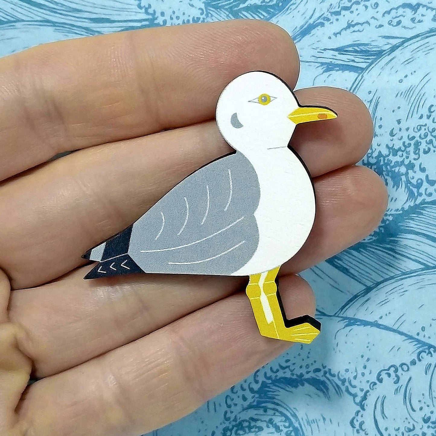 Wooden seagull pin badge held on hand